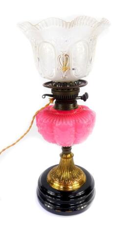 A Victorian brass oil lamp converted to electricity, with a pink fluted glass reservoir, moulded with flowers and bows, moulded and etched floral frosted glass shade, 47cm high.