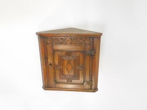 A Victorian oak hanging corner cupboard, with arched decoration, and single panel door opening to reveal a shelfless interior, 6cm wide, 30cm deep, 36.5cm high.