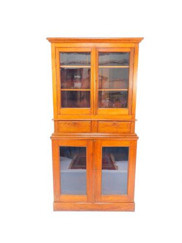 A Victorian oak bookcase, the outswept pediment above two doors, opening to reveal two shelves, above two drawers, raised over a further pair of cupboard doors, opening to reveal a single shelf on a plinth base, 98cm wide, 44cm deep, 195.5cm high.