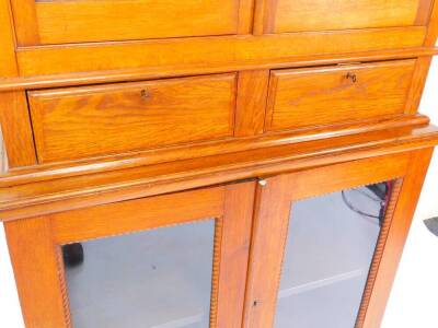 A Victorian oak bookcase, the outswept pediment above two doors, opening to reveal two shelves, above two drawers, raised over a further pair of cupboard doors, opening to reveal a single shelf on a plinth base, 98cm wide, 44cm deep, 195.5cm high. - 4