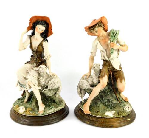 A pair of Capodimonte porcelain figures of a shepherd and shepherdess, monogrammed, raised on a circular wooden socle base, 30.5cm high.