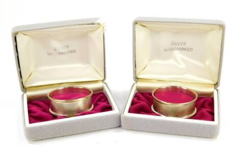 A pair of silver napkin rings, with engine turned decoration, rectangular reserve, boxed, Birmingham 1985, 0.72oz.