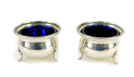 A pair of George V silver circular salts, with blue glass liners raised on three paw feet, Birmingham 1913, 1.74oz.