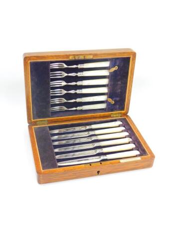 A set of six George V silver fruit knives and forks, with mother of pearl handles, oak cased, Sheffield 1913.