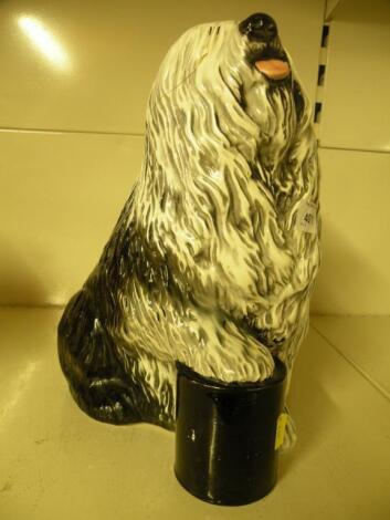 A Beswick Dulux dog standing on a later painted black tin of