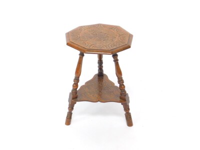 An Arts & Crafts style oak tripod table, the octagonal carved top with carved decoration, raised on turned legs united by a shaped under tier, similarly carved, 62cm high, 41cm wide.