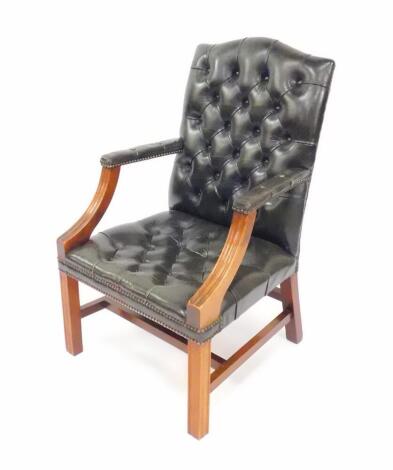 A Georgian style mahogany and green leather open armchair, with button back, over stuffed seat and arm rests, raised on square fluted legs, united by an H frame stretcher.