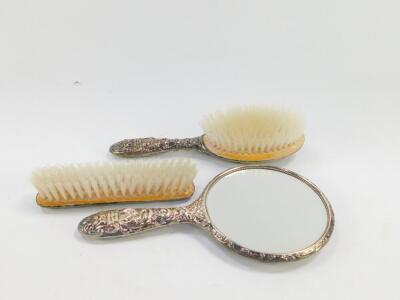 A silver backed three piece dressing table set, embossed with masks, birds and foliate scrolls, comprising hand mirror, clothes and hair brushes, Birmingham 1979. - 2