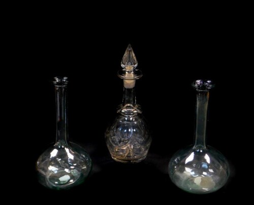 A Victorian cut glass decanter and stopper, with engraved decoration, 32cm high, together with a pair of moulded glass carafes, 27.5cm high. (3)