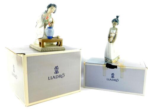 A Lladro porcelain figure modelled as a Oriental girl, 0840, and another of a girl holding a kitten in her arms, both boxed. (2)