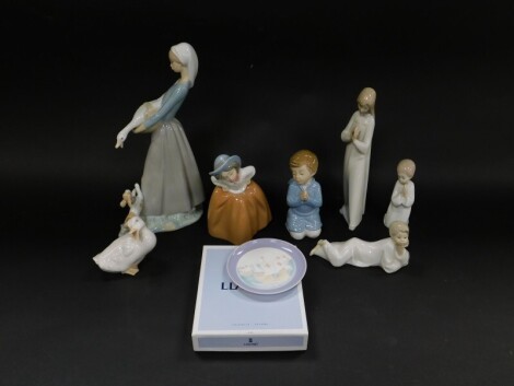 Lladro Nao porcelain figures, including a girl with a puppy and goose, No 866, boxed., kneeling children in prayer, and a Lladro porcelain plate Three Carabels, 05964, boxed. (quantity)