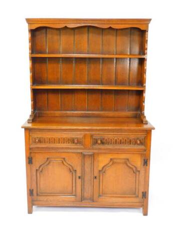 A Thomas Clarkson & Son oak dresser, the two shelf plate rack over two carved drawers over panelled cupboard doors, raised on square legs, 188cm high, 121.5cm wide, 47.5cm deep.