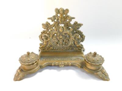 A Victorian style brass desk stand, cast with cherubs, fruit and flowers, with letter rack pen tray and pair of ink wells, 30cm wide. - 2