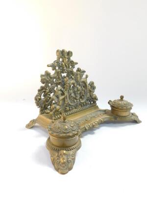 A Victorian style brass desk stand, cast with cherubs, fruit and flowers, with letter rack pen tray and pair of ink wells, 30cm wide. - 3