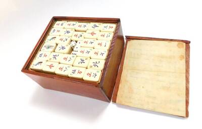 An early 20thC mahogany cased bamboo and bone Mahjong set.