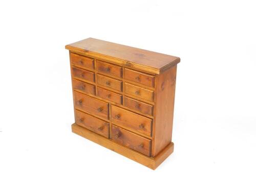 A pine table top chest, of nine short over four medium drawers, raised on a plinth base, 65cm high, 69cm wide, 23cm deep.