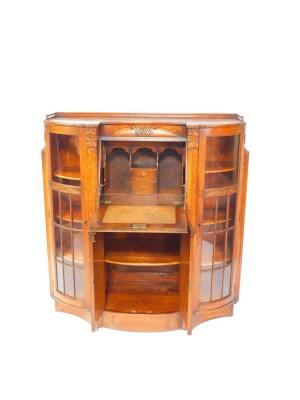 A Continental early 20thC oak bureau cabinet, carved with flowers, the central fall flap opening to reveal drawers and recesses, over a pair of bow fronted cupboard doors, flanked by two glazed doors, opening to reveal six shelves, raised on a plinth base - 2