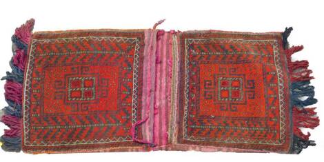 A Turkish Kelim red ground saddle bag, decorated with guls and geometric motifs, 132cm x 53cm.