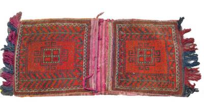 A Turkish Kelim red ground saddle bag, decorated with guls and geometric motifs, 132cm x 53cm.