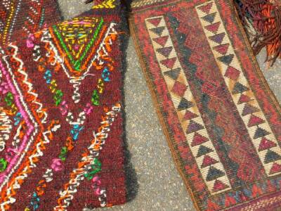 A course wool rug, decorated with a geometric pattern against a red and black ground, 147cm x 113cm, together with a Caucasian saddle rug, with beaded tassel fringes, 143cm x 27cm. - 3