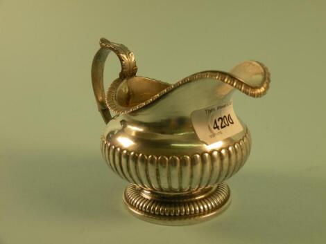 A George IV silver part fluted milk jug with acanthus cast thumb piece