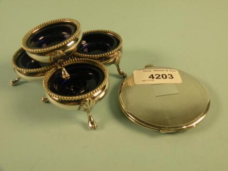 A silver engine turned powder compact and a set of four silver plated salts