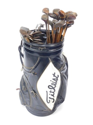 A large Titleist golf or display bag, containing a collection of vintage drivers, mainly wooden shafted, and a selection of wedges and irons, all wooden shafted. (39)