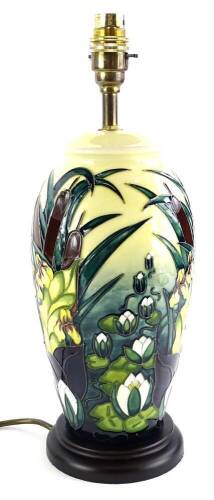 A Moorcroft pottery lamp base, decorated with rushes and lilies, on a cream ground with brass fitting and composite base, 38cm high overall.