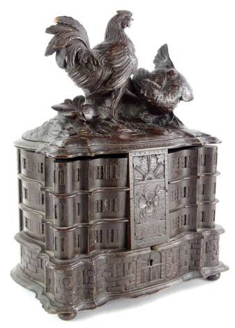 A late 19thC/early 20thC Black Forest carved jewellery box, the hinged lid decorated with chickens, leaves, etc., enclosing a fitted interior with six separate compartments, overall carved to simulate a house or country house on bun feet (AF), 38cm high, 
