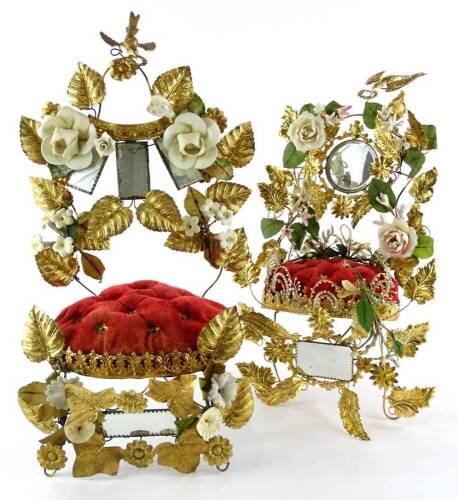 Two similar late 19th/early 20thC French marriage crown cushions, each decorated with gilt metal flowers etc. embellished with ceramic flowers, surrounding various mirrors, 47cm high.