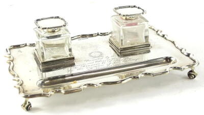 A George V silver presentation ink stand, of rectangular form with a shaped edge and two glass square section wells, engraved "presented by the employees tenants and others on the Knoydart Estate to Francis E J Bowlby on occasion of his marriage 6th Septe