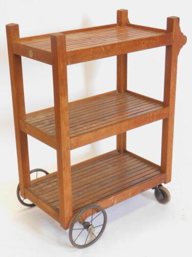 A teak slatted three tier trolley, on spoked wheels, label for Castles Ship Breaking Company Manufacturers, 160 Millbank, London, 79cm wide.