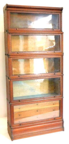 An early 20thC oak Globe Wernicke five section bookcase, with typical hinged glazed doors, the lower section with three frieze drawers on a plinth base, label for Wernicke System Elastic Bookcase, showing various patents relating to the late 19thC, 195cm