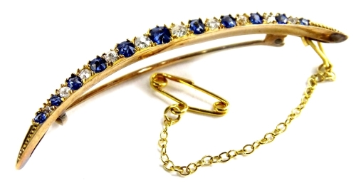 A sapphire and diamond set crescent brooch, with various old cut sapphire and diamonds, in claw setting, on single pin back, with safety chain, yellow metal, unmarked, 5.5cm wide, 3.6g all in.