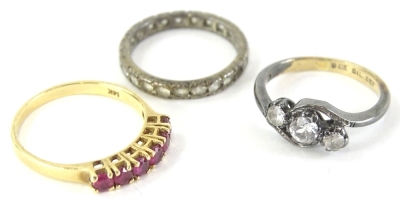 Three dress rings, comprising a ruby set half hoop eternity ring, yellow metal stamped 14K, with size round brilliant cut rubies, together with a 9ct gold and silver crossover dress ring and a further eternity ring, unmarked, the 14ct ring 3.4g all in (3)