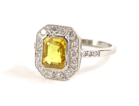 A yellow sapphire and diamond dress ring, with rectangular cut yellow sapphire, 7.2mm x 5.4mm x 3mm, approx 1.7cts, surrounded by twelve round brilliant cut diamonds, with three round brilliant cut diamonds to each shoulder, the diamonds totalling approx 