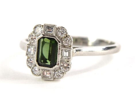 A modern green tourmaline and diamond dress ring, the ring head with rectangular cut green tourmaline 5.2mm x 4mm x 2.2mm, surrounded by diamonds, four square cut and eight round brilliant cut, ring size O, 4g all in, boxed.