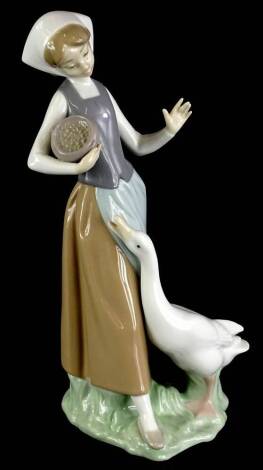A Lladro porcelain figure of a young girl feeding a goose, numbered to underside 1052, 23cm high (boxed).