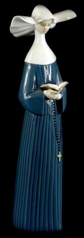 A Lladro porcelain figure of a nun, wearing a blue gown, numbered to underside 5500, 26cm high (boxed).