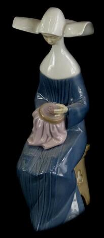 A Lladro porcelain figure of a seated nun doing embroidery, numbered to underside 5501, 20.5cm high (boxed).