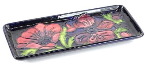 A Moorcroft pottery rectangular dish, decorated with poppies on a navy ground, numbered to underside 34/94, 20cm wide.