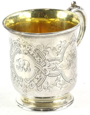 A mid Victorian silver christening mug, engraved overall with scrolls, flowers, etc. and with initials to the central cartouche, gilt interior and scroll handle, London 1859, 5oz, 8cm high.