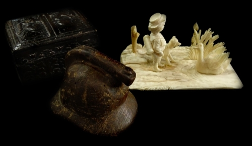 A late 19thC carved ivory figure group of a young boy, a dog and a swan, on a rectangular base, possibly Dieppe 10 cm long, a carved wooden miniature Fireman's helmet and a stamp box model with figures playing pipes etc. (3).