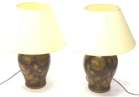 A pair of terracotta baluster shaped Indian style table lamps, each decorated with flowers on a red ground with cream shades, 67cm high.