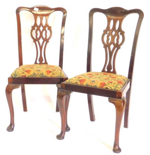 A pair of early 20thC mahogany dining chairs in George III style, each with a pierced splat, a drop in seat, on cabriole legs, with pad feet.