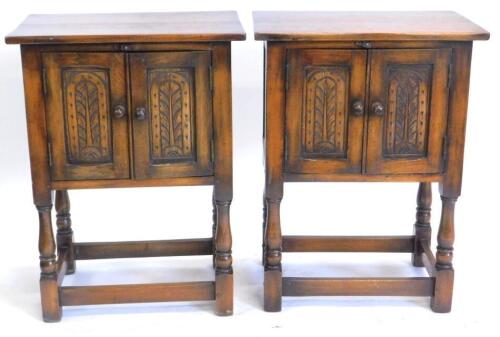 A pair of oak Bevan Funnell side cabinets, each with two carved panelled doors on turned supports, 68cm high, 32cm deep, 52cm wide.