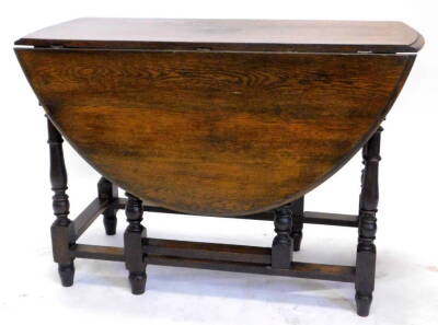 An oak oval drop leaf table, the top with a moulded edge on turn supports, 103cm wide.