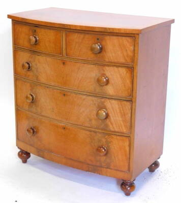 A Victorian mahogany bow front chest of drawers, with a plain top, above two short and three long drawers, each with turned wood handles on bun feet, 95cm wide.