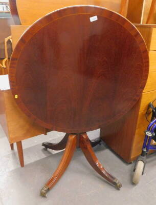 A mahogany tilt top table, on paw feet.