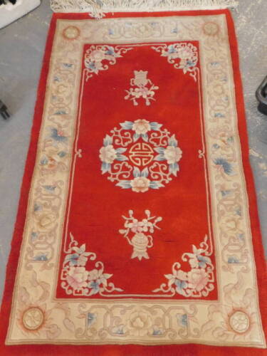 A modern Chinese rug, on red ground, with cream border.